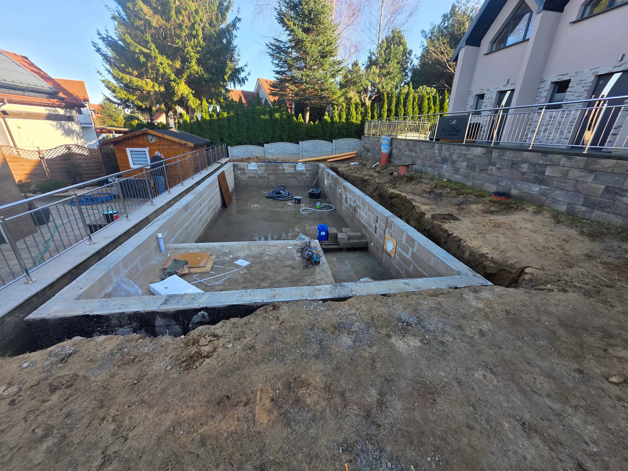 Murowana niecka basenu z bloczków betonowych w otwartym wykopie, z wydzielonym brodzikiem dla dzieci — realizacja JML-SPA w Rewalu przed hydroizolacją i montażem folii